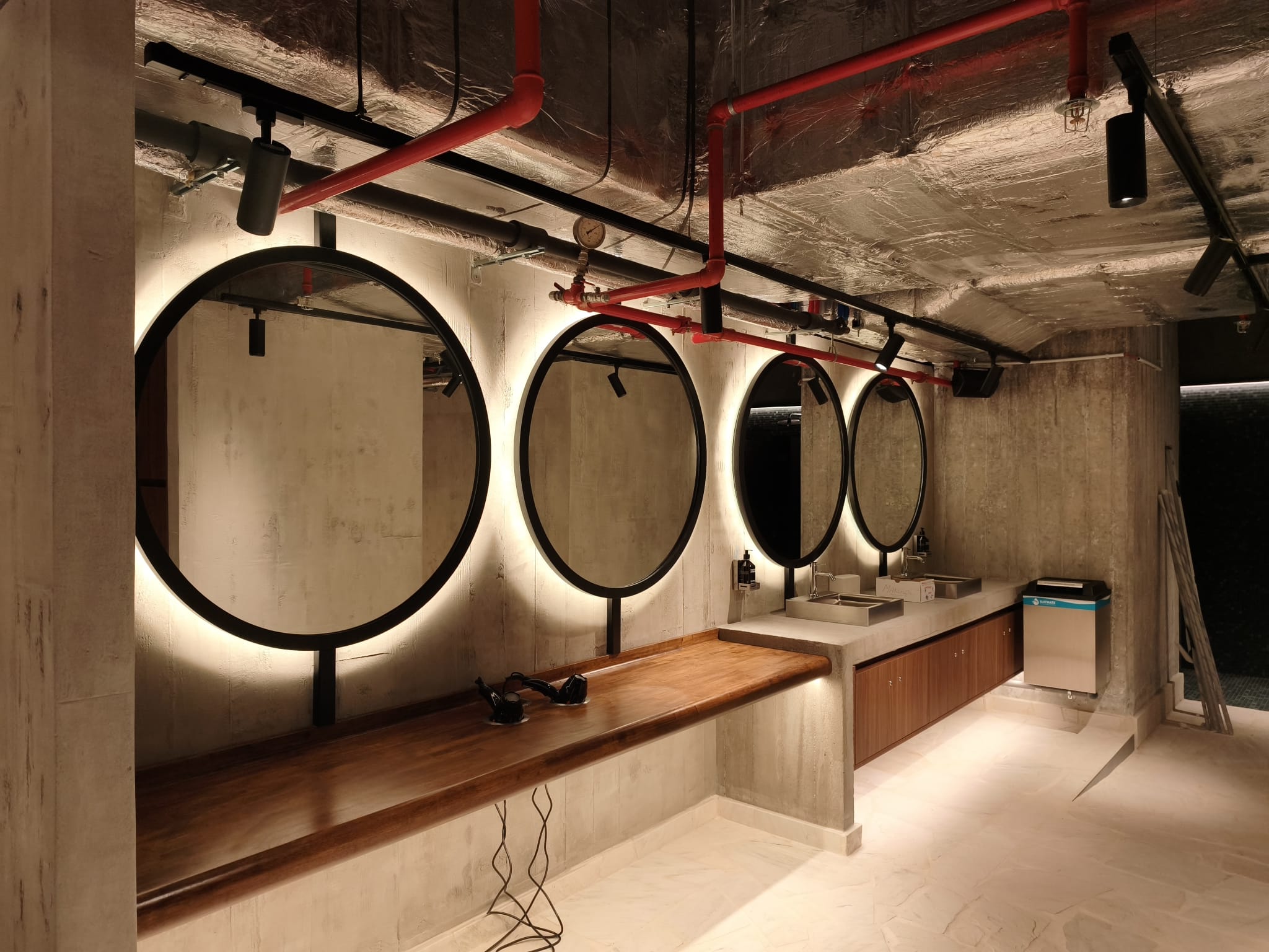 Vestiaire : béton banché, techniques apparentes, miroirs rétroéclairés